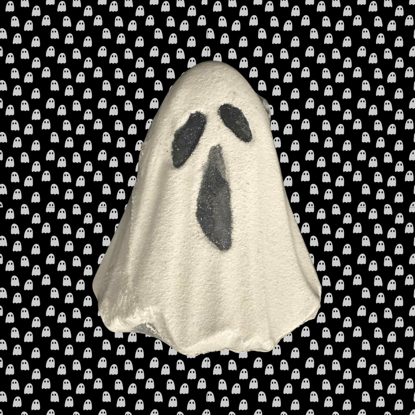 Ghost-shaped bath bomb on a black background with white ghost pattern