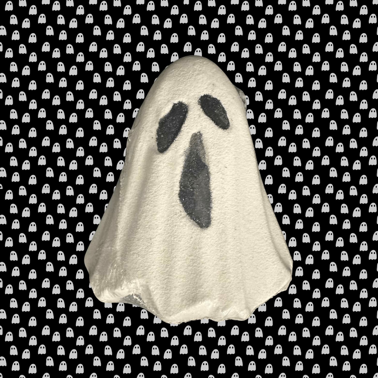 Ghost-shaped bath bomb on a black background with white ghost pattern