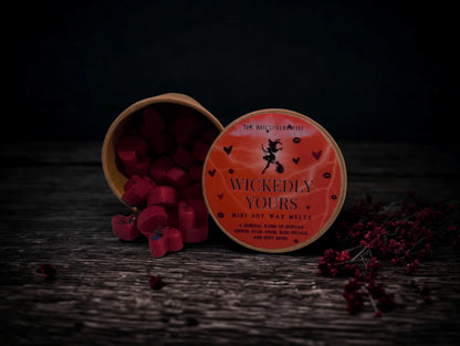 Wickedly Yours wax melts packaging on a dark wooden surface with red berries.