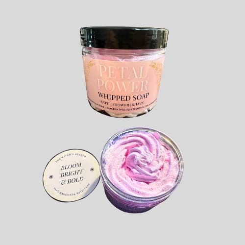 Pink whipped soap in a jar with a black lid on a light gray background