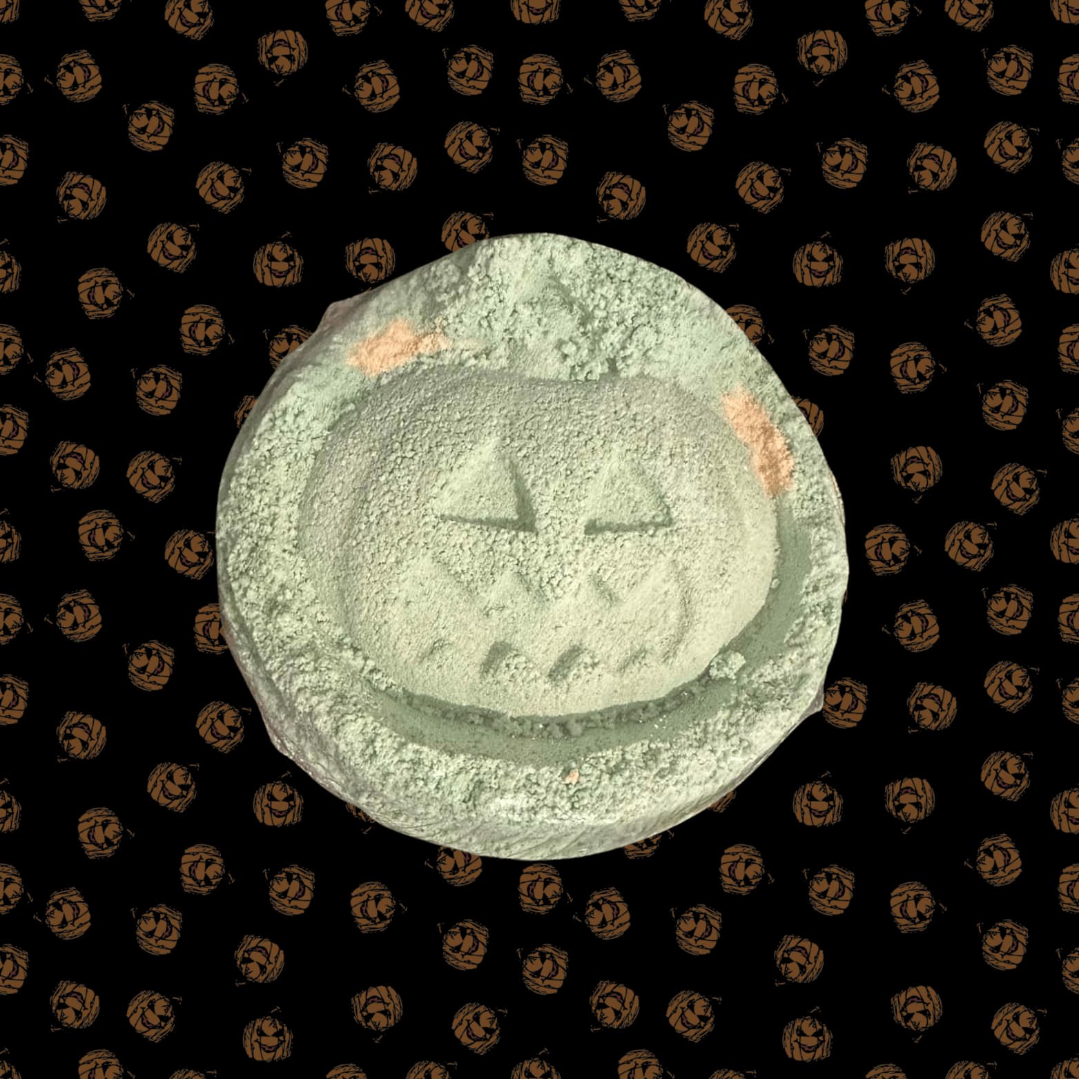 Green and orange pumpkin bath bomb on a Halloween-themed background