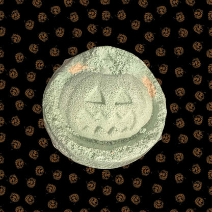 Green and orange pumpkin bath bomb on a Halloween-themed background