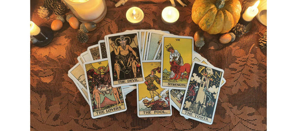 Tarot cards on a table with candles and pumpkins, creating a mystical atmosphere.