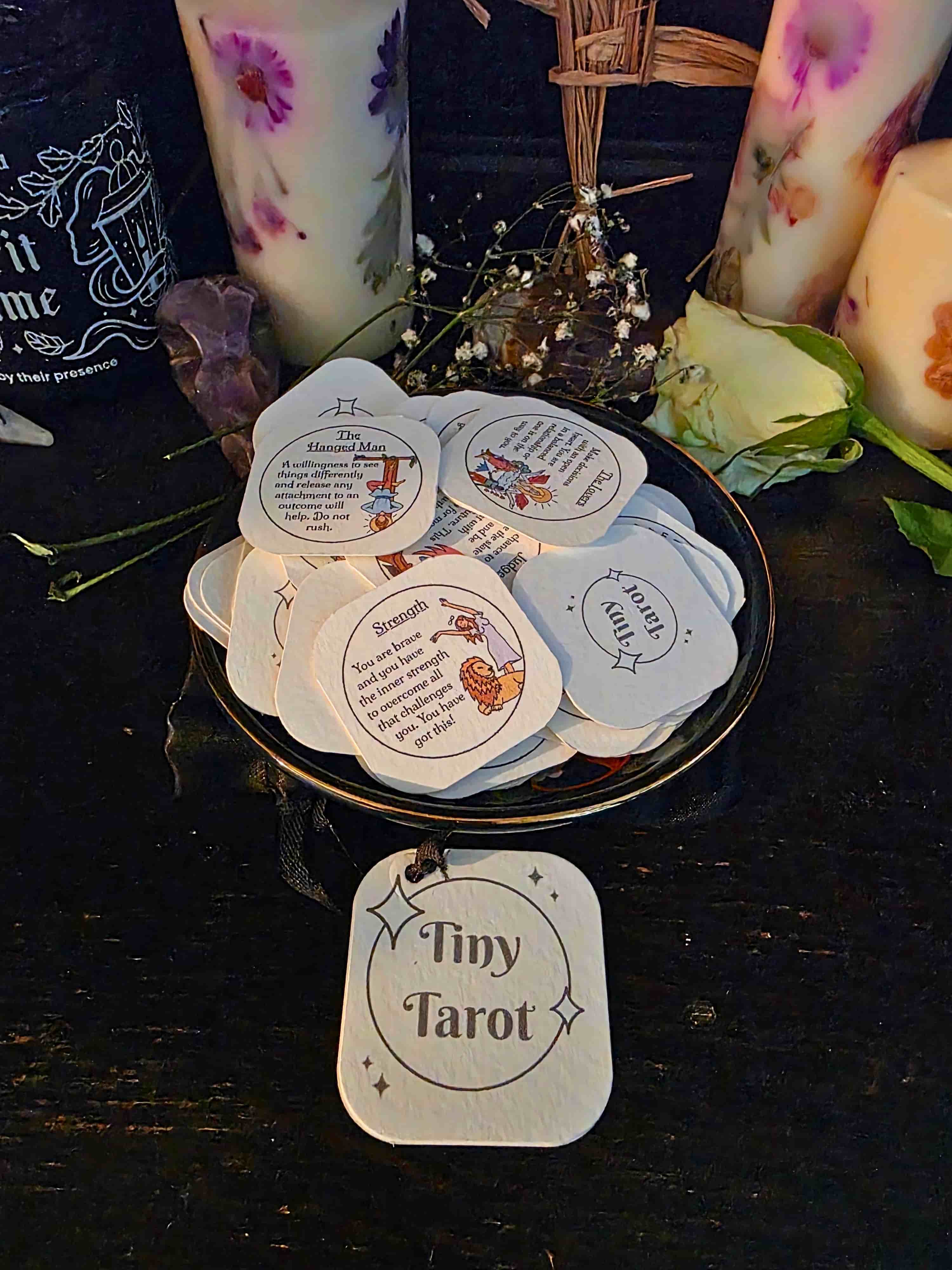 Collection of 'Tiny Tarot' cards on a dark surface with candles and decorative items.
